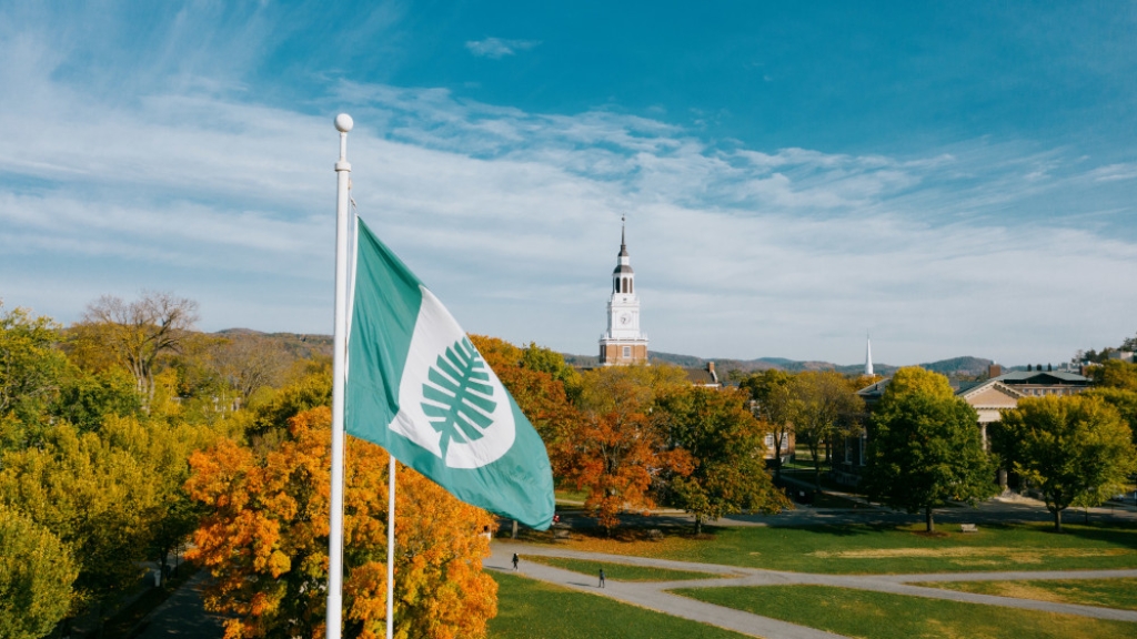 A Dartmouth flag with campus in the background during autumn